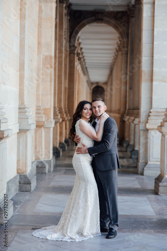 Fashion photo. Young elegant sexy couple hugs, wearing suit and  white dress with a train, enjoy their honeymoon, luxury style, love, stylish lovers. Love story. Lifestyle concept.