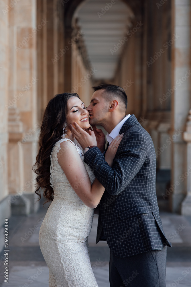 Young fashion couple posing. Young elegant sexy couple hugs, wearing suit and white luxury dress, enjoy their honeymoon, luxury style, love, stylish lovers.  Feelings of love between two people. 