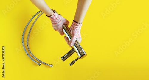 Woman holding in hands to repair faucet with cotton work gloves on. Isolated on yellow background.  © NoonBusin