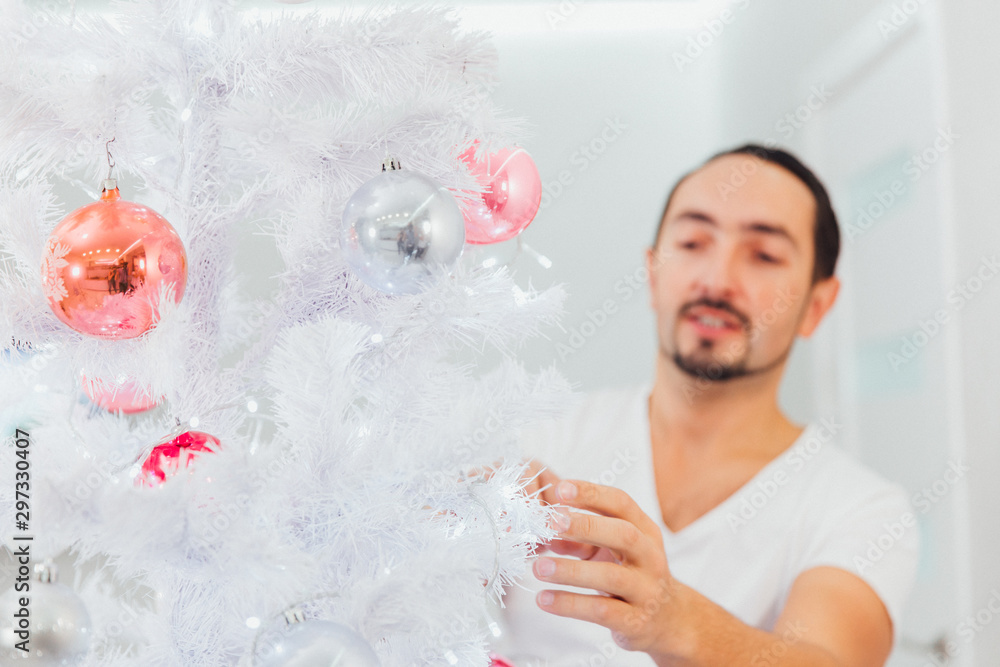 Fototapeta premium man dresses up Christmas tree. Christmas time