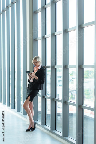 Business women using smart phone or mobile to work and checking information of financial data and connection technology in model office city town. Business Concept.