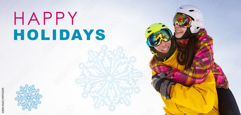 title - happy holidays! Young happy couple in snowy mountains. Winter sport vacation. activity holiday concept. the girl hugs the guy and they are in ski helmets, masks and bright clothes.