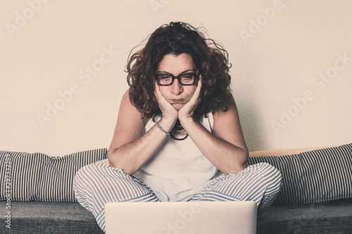 Weary woman works with laptop at home New technology fails and breaks down disappointing Girl can't do shopping on line internet don't works New trends technology e-commerce and disappointment concept photo