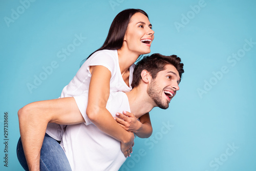 Close-up profile side view portrait of his he her she nice attractive lovely cheerful cheery couple piggybacking having fun isolated on bright vivid shine vibrant blue turquoise background