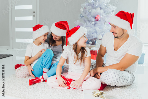 Happy parents and children exchanging gifts near Christmas tree at home