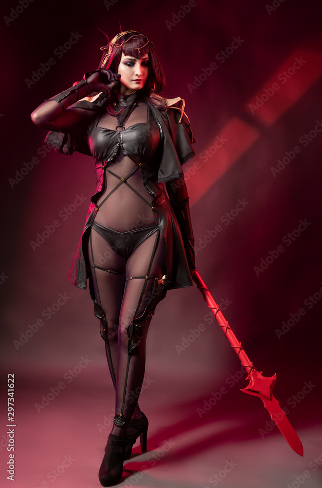 Beautiful leggy busty cosplay girl wearing an erotic leather costume posing  with a fake spear on a red background in theatrical smoke. Stock Photo |  Adobe Stock