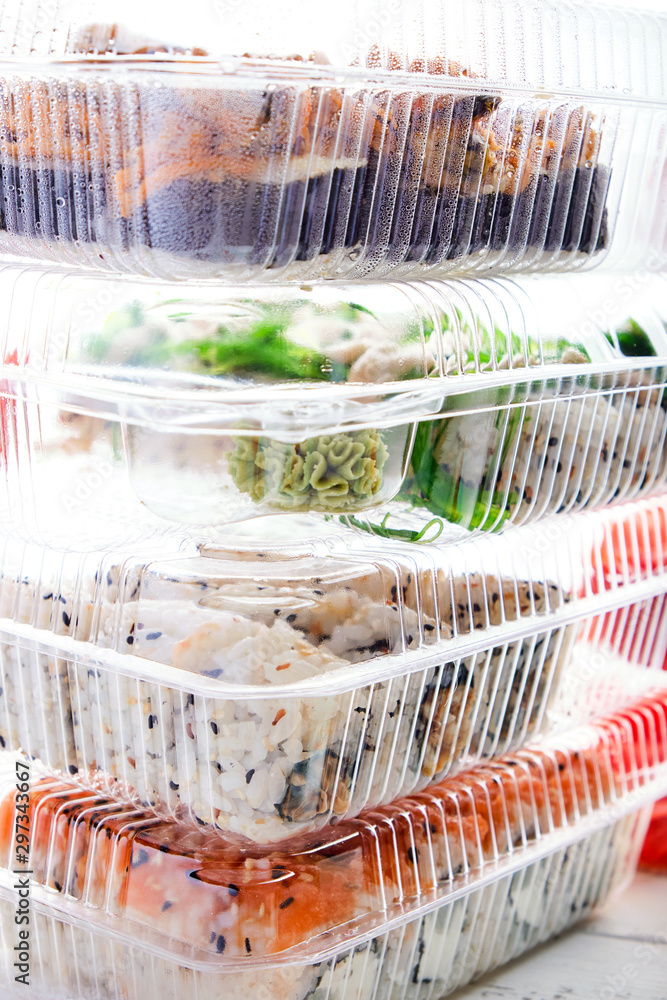 Stack of plastic boxes with sushi roll sets. Food delivery