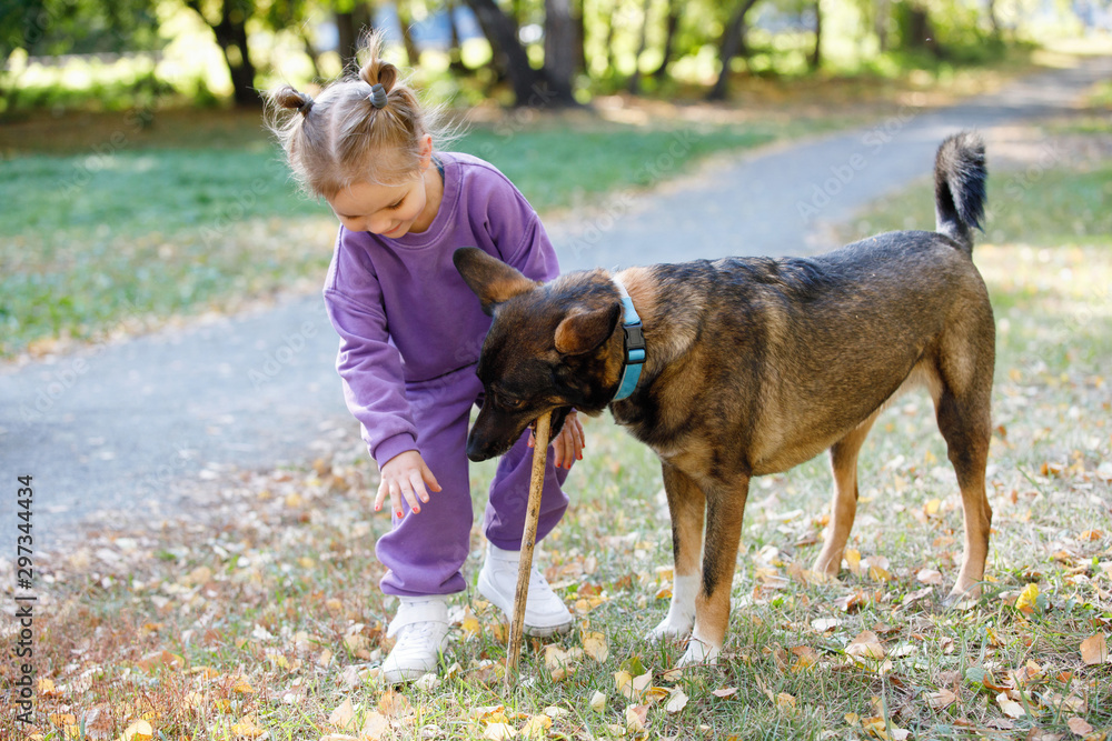 Little girl with dog in a city park.