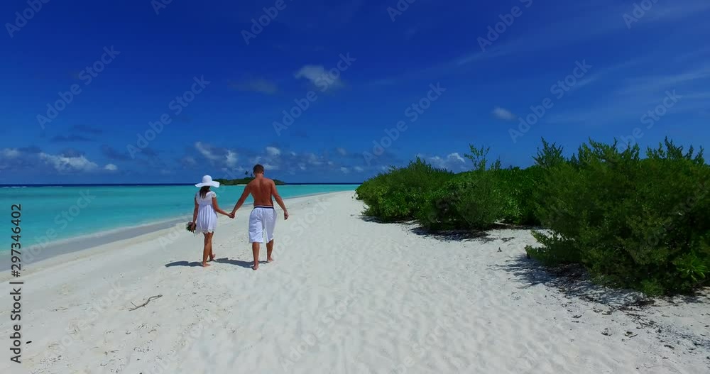 Young couple holding hands walking on white sandy beach along coastline in Philippines Young couple holding hands walking on white sandy beach along coastline in Philippines
