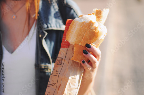 Beautiful girl eat baguette on the street