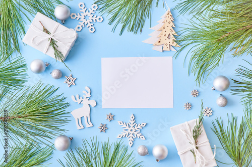 Mockup white greeting card with pine branches and gift box on a blue background