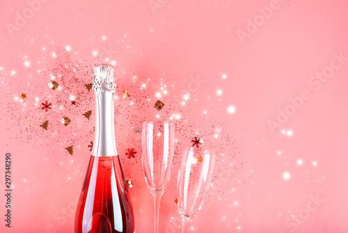 Christmas concept. Pink champagne, sparkles and a pair of glasses.