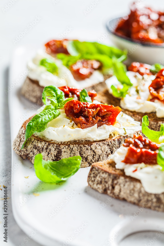 Sandwiches with cottage cheese and sun-dried tomatoes on white board.