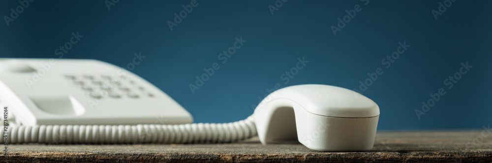 Wide view image of white landline telephone handset of the hook Wide view image of white landline telephone handset of the hook