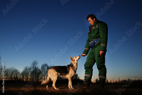 Man with dog at walk on th field in sunset