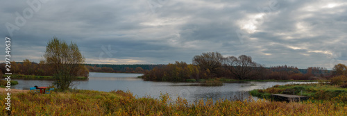 Panoramic view on Volga river with small island and dramatic green, orange and yellow forest during autumn day, Tver region, Russia