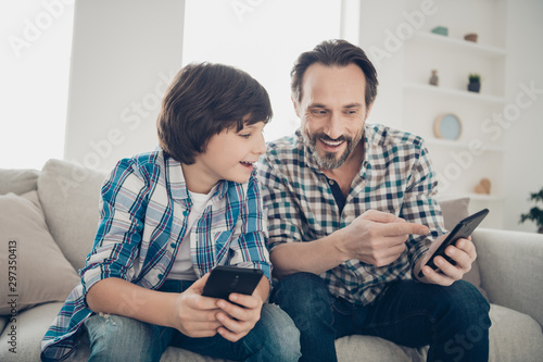 Sms message modern technology digital world generation concept. Photo of mature bearded excited guy showing new social page site shop with electronic toys to his younger son sitting on divan photo