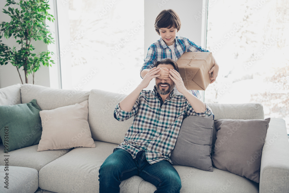Portrait of two nice attractive cheerful cheery glad guys daddy pre-teen  son hiding carton box for dad's day occasion in light white modern interior  house living-room indoors Stock Photo | Adobe Stock