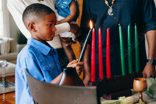 Boy lights candle to celebrate Kwanzaa photo