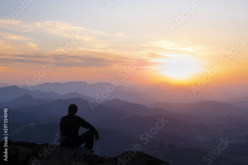 Man on top of the mountain at sunset.