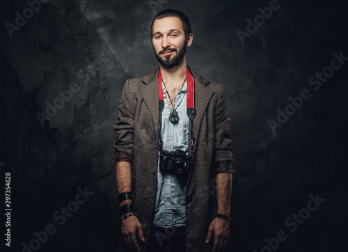 Portrait of smiling bearded reporter with photo camera on the dark background. © Fxquadro