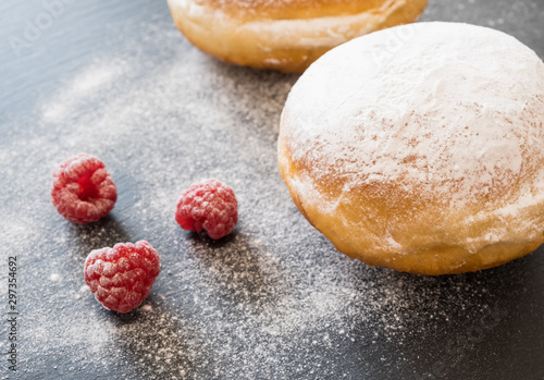 Beignets/german donuts - berliner with raspberries and powdered sugar on the dark background