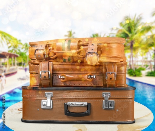 Retro suitcase with travel objects on wooden desk in beach background