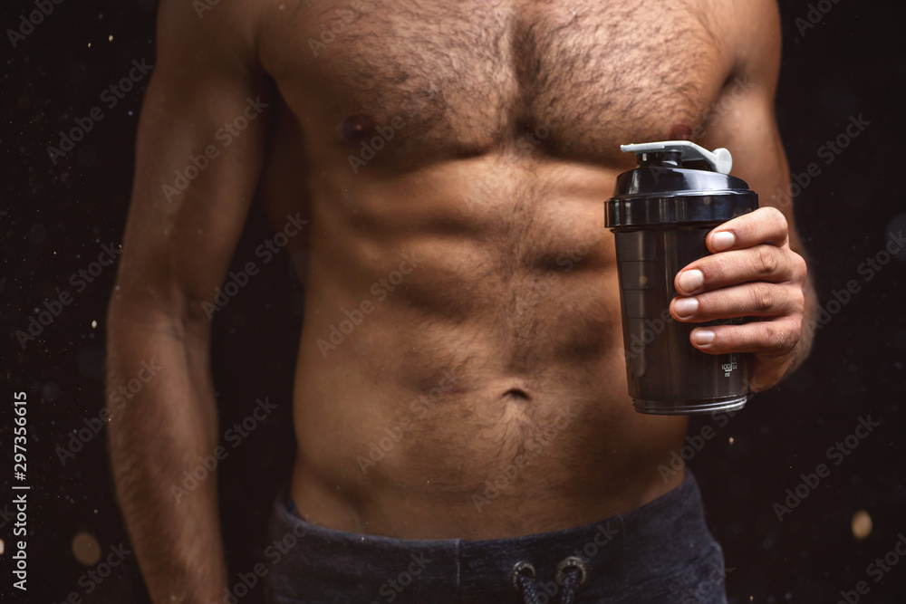 Shirtless torso of a muscular man with a shaker in one hand Shirtless torso of a muscular man with a shaker in one hand