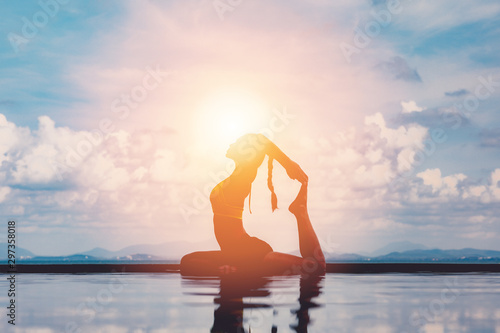 Obraz na plátně silhouette Athletic Asian woman relaxing in yoga king pigeon pose on the pool ab