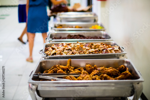 Array of dishes in stainless steel trays, like fried chicken, sliced "lechon baboy" or roasted or suckling pig, "dinuguan" or pork blood stew. Selective focus. Copy space.