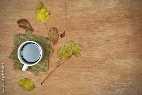 Autumn composition concept. Cup of coffee with autumn leaves on wooden background.