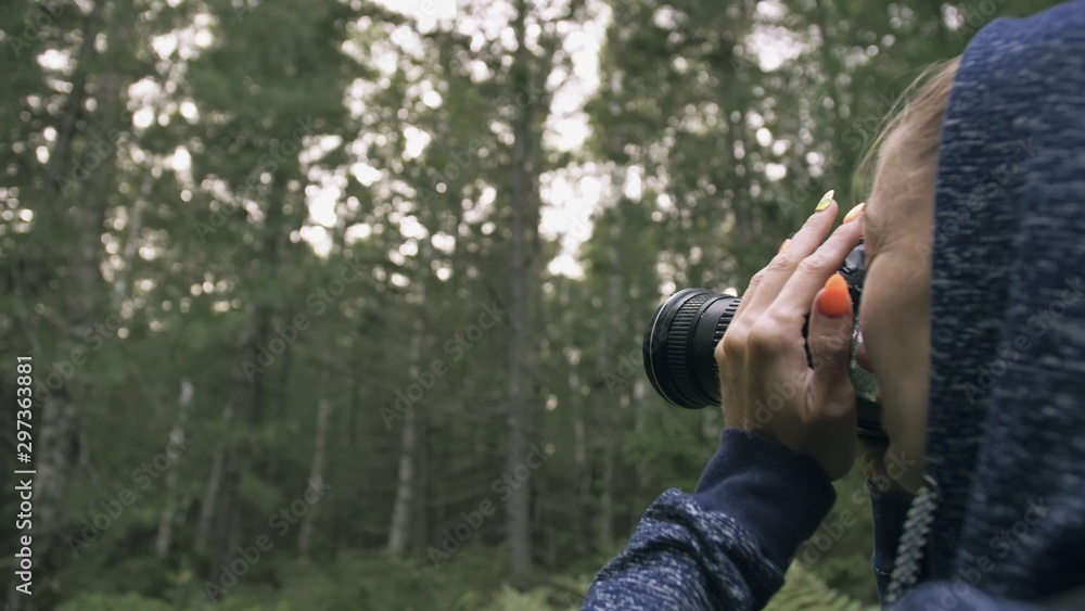 Traveler photographing scenic view in forest. One caucasian woman shooting close up look. Girl take photo video on dslr mirrorless camera.