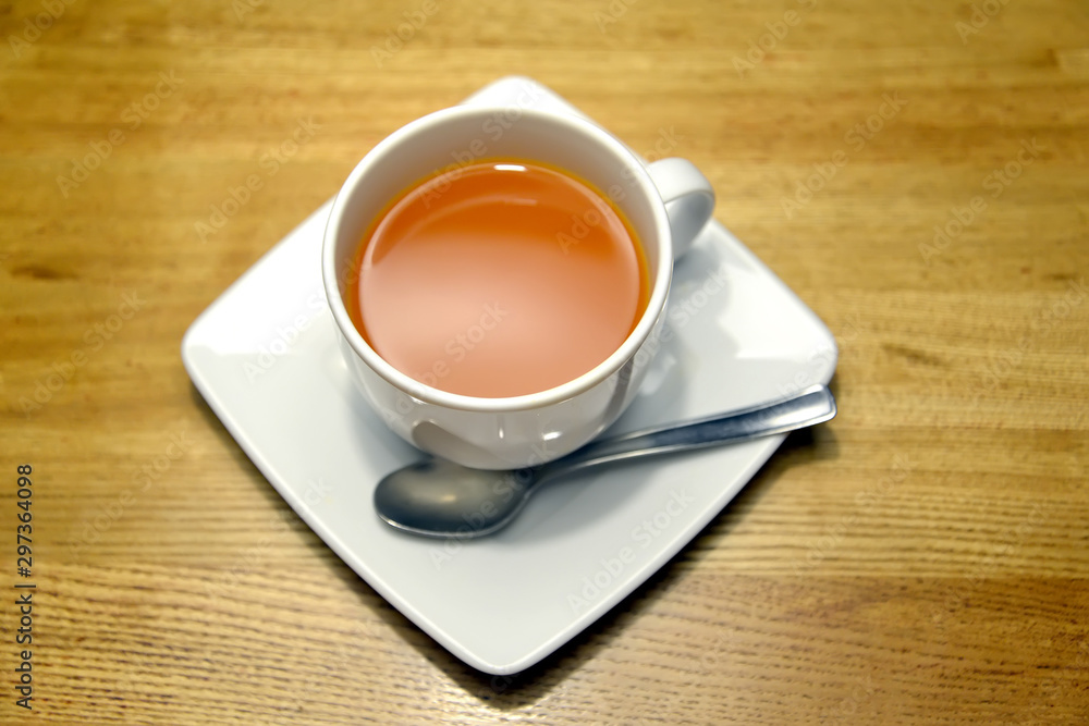 White cup with sea-buckthorn tea stands on a saucer White cup with sea-buckthorn tea stands on a saucer