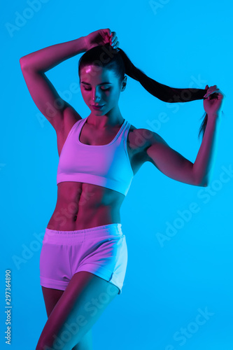 Sporty young girl posing on blue background.
