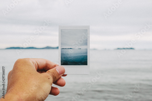 Close up of man's hand holding photograph of sea