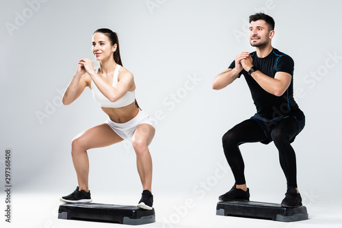 Fototapeta Naklejka Na Ścianę i Meble -  Athletic couple doing exercises over steps in aerobic class isolated on white background. Sport and health concept.