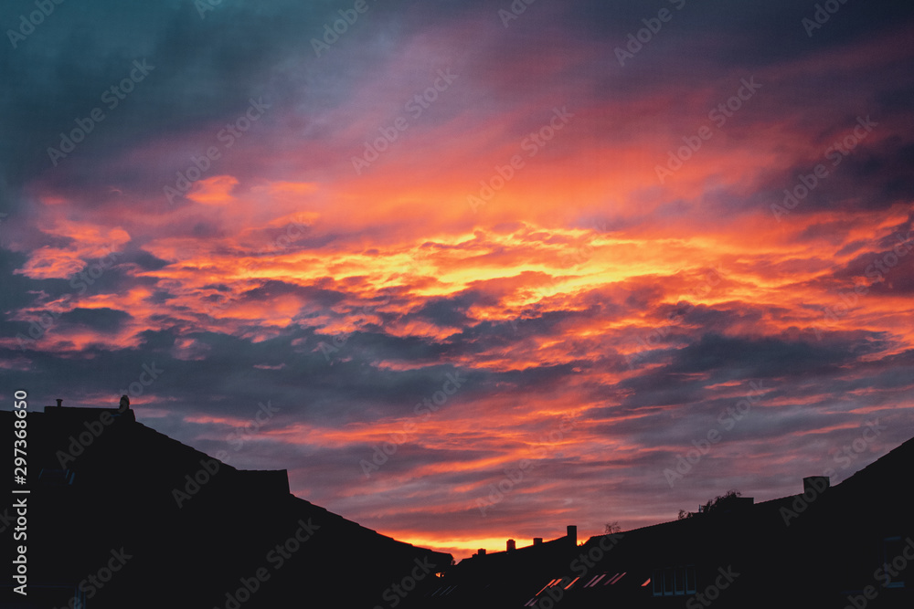 Dramatic colorful evening sky from sunset and purple clouds over the urban roof top houses