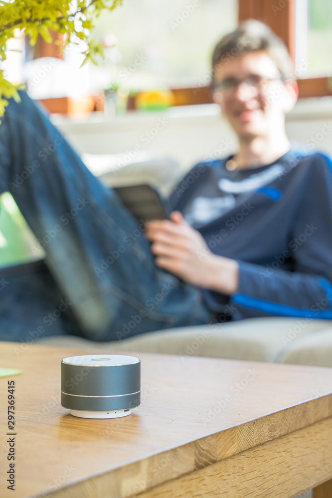 Fototapeta premium Smart ai speaker with child playing on tablet in the backround. Smart home concept
