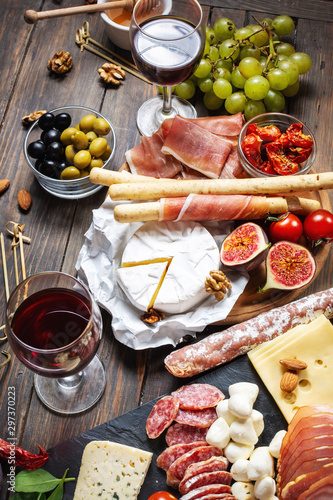 Italian antipasto with prosciutto, ham, cheese, olives and grissini breadsticks on wooden background