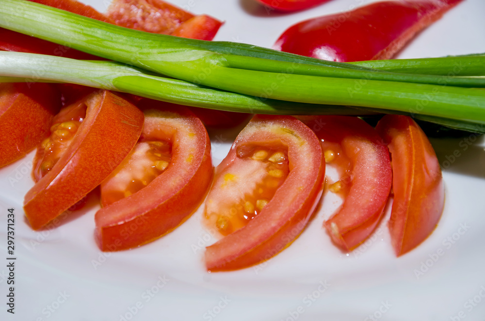 chopped tomatoes and green onions on a plate, close-up.