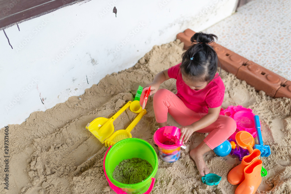 Little girl play sand at the front home,Time for relax,Thailand people,Have a fun on a holiday Little girl play sand at the front home,Time for relax,Thailand people,Have a fun on a holiday