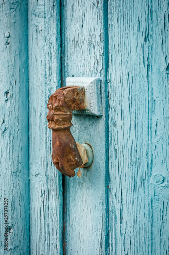 Fotografie rusty hand shaped door knocker on wooden door with weathered blue paint in tradi
