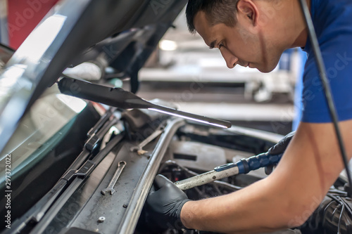 Car mechanic repairer service technician checks and repairs auto engine © guruXOX