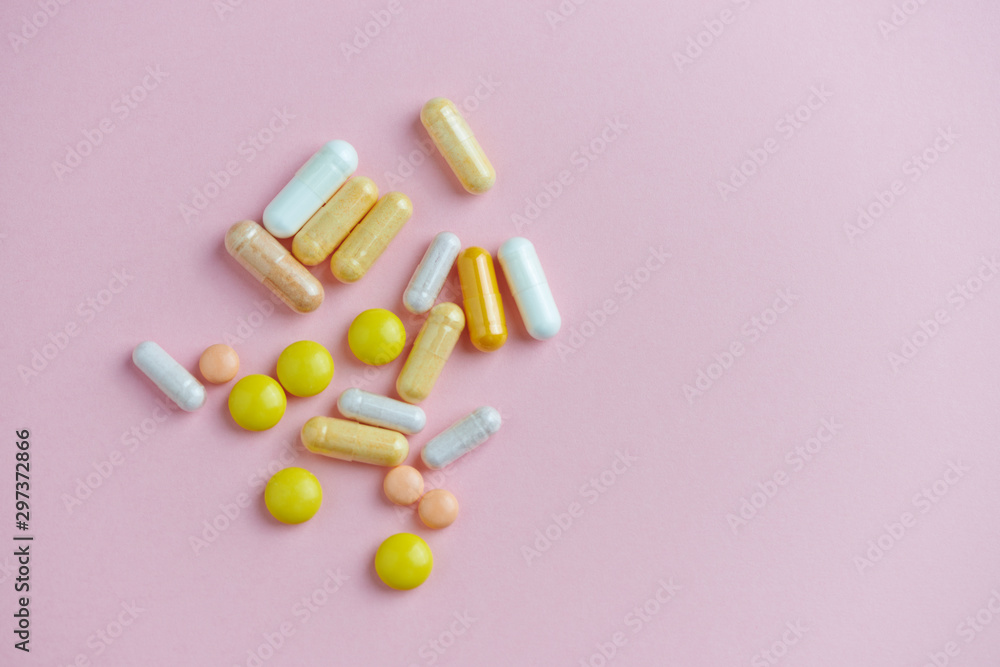 Multicolor vitamins and supplements on bright paper background. Concept for a healthy dietary supplementation. Copy space. Multicolor vitamins and supplements on bright paper background. Concept for a healthy dietary supplementation. Copy space.
