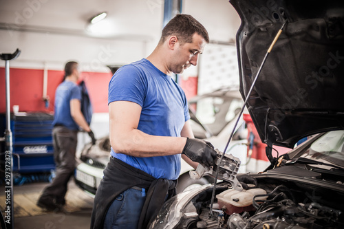 Two car mechanic repairers service technician repairs auto engine