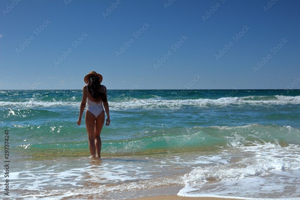 seascape young woman in swimsuit and hat goes into the sea seascape young woman in swimsuit and hat goes into the sea