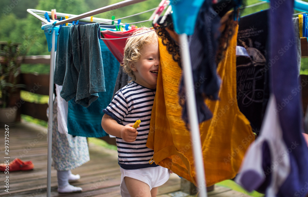 Toddler children outdoors in summer, playing with clothes drying hanger.