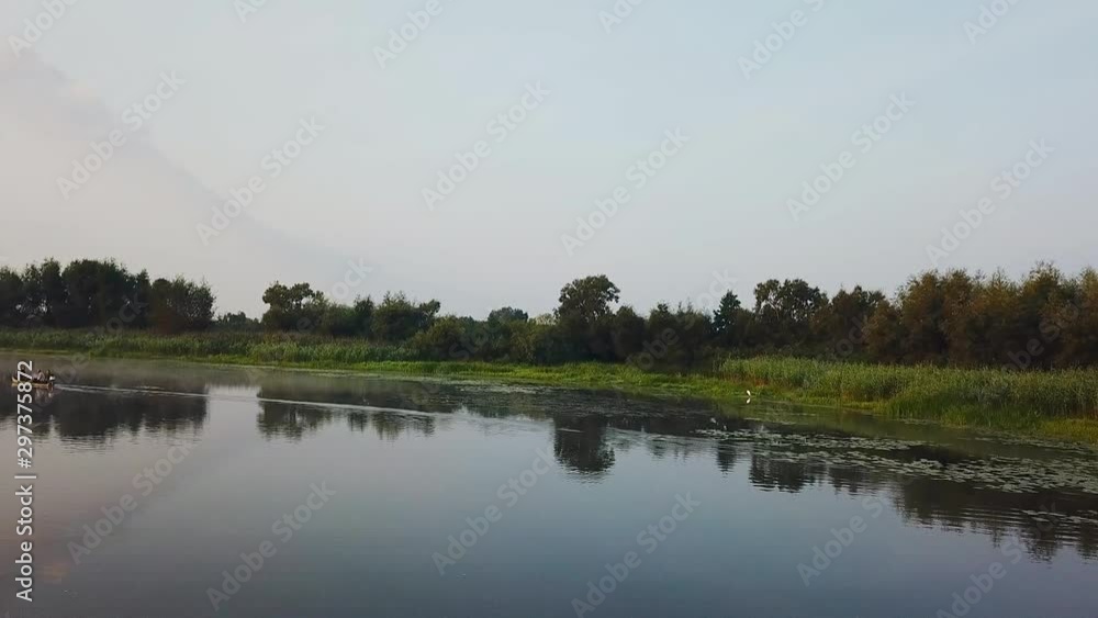 old boats in the morning fog at sunrise, orange sunrise over river with wooden boats, fog over the marsh at dawn, morning mist over lake, 