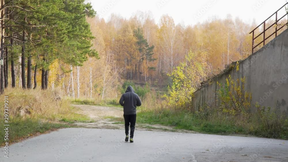 A young hoodie runner at a morning workout in an autumn park on a sunny day. 4k footage. A young hoodie runner at a morning workout in an autumn park on a sunny day. 4k footage.