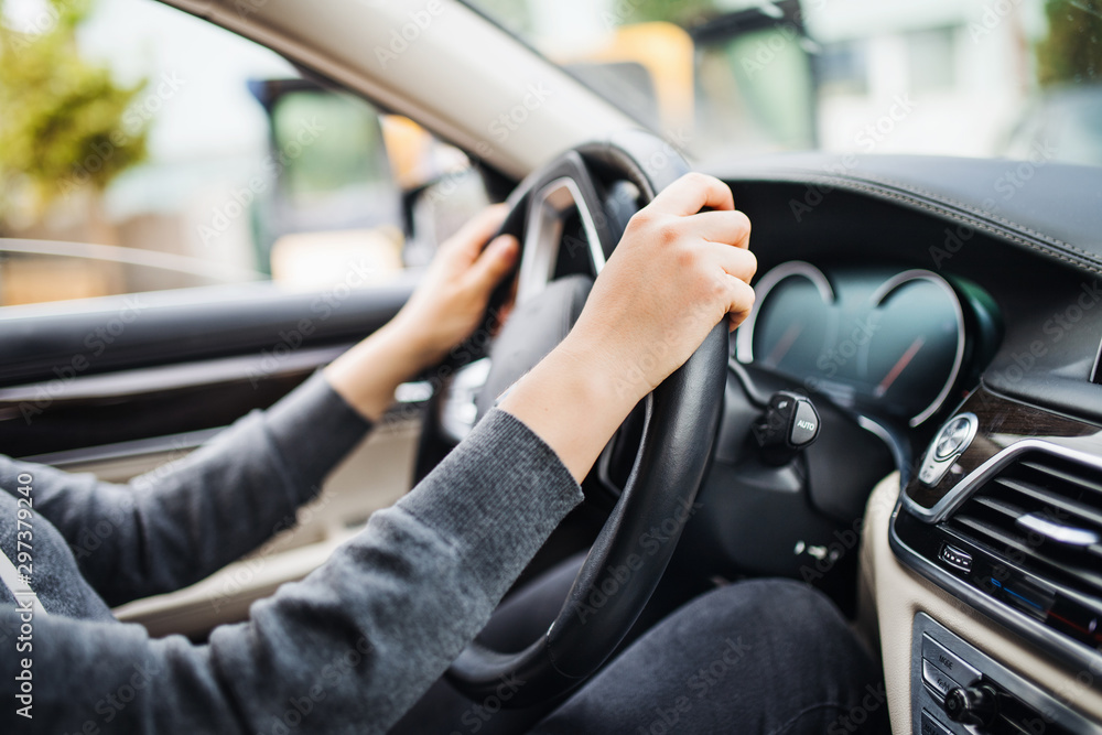 Midsection of arms of young woman driver sitting in car, driving.